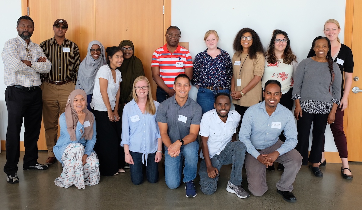 16 staff members representing 6 community-based organizations smile at the camera