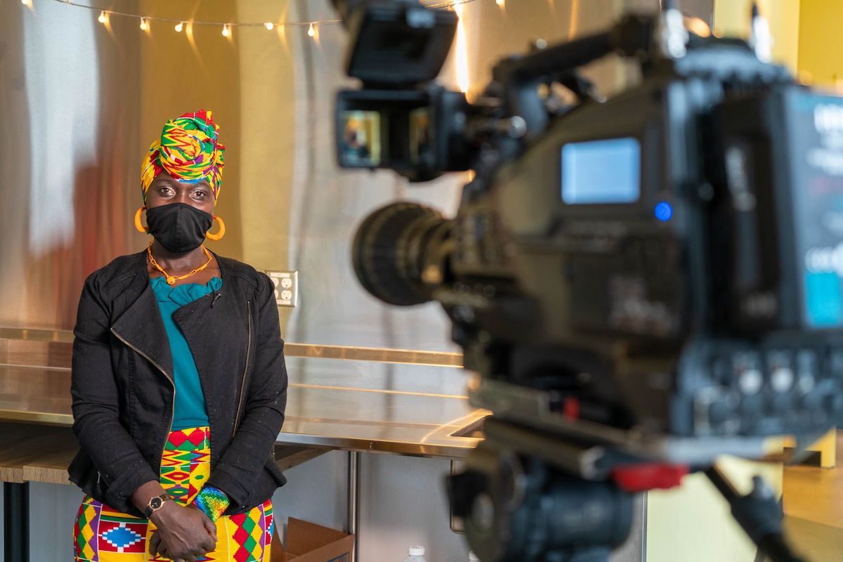 A woman wearing brightly colored clothing looks at a camera.